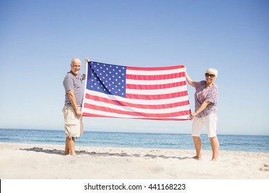 Senior couple holding american flag together on beach - Powered by Shutterstock