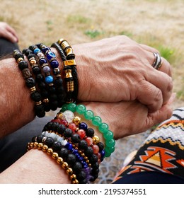 Senior Couple Holding Hands. They Are Both Fond Of Breaded Bracelets. Pair Look