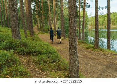 senior couple holding hands walking in forest along lakeside - Powered by Shutterstock