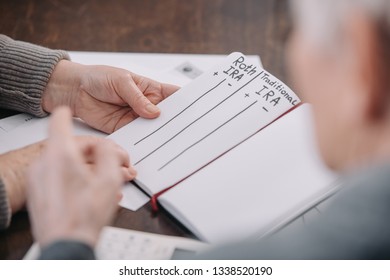 Senior Couple Holding Notebook With Roth Ira And Traditional Ira Words