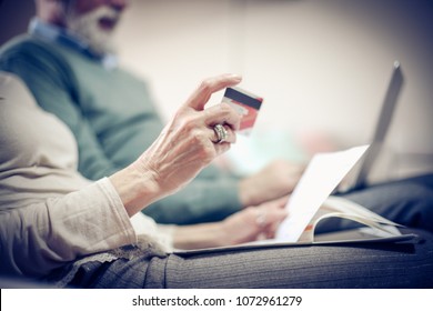 Senior Couple At Home Checking Finance On Credit Card.  Close Up. Focus Is On Hand.