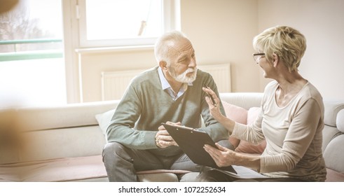 Senior Couple At Home With Document And Contractor.