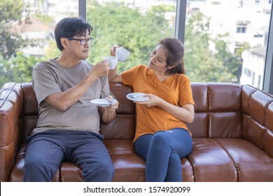 Senior Couple At Home , Enjoying Spending Time Together. Living Room Background. Generation Modern Technology Retirement Romantic Healthy Concept. Asian Middle Age. Enjoying Tea Time. Smiling Gesture