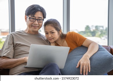 Senior couple at home , enjoying spending time together. Living room background. Generation Modern technology Retirement Romantic Healthy concept. Asian middle age. Serious attitude. Bad news. - Powered by Shutterstock