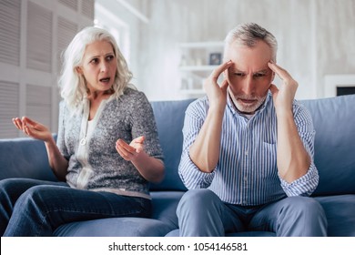 Senior couple at home. Handsome old man and attractive old woman are having relationship problems. Sitting on sofa together while quarrel. - Powered by Shutterstock