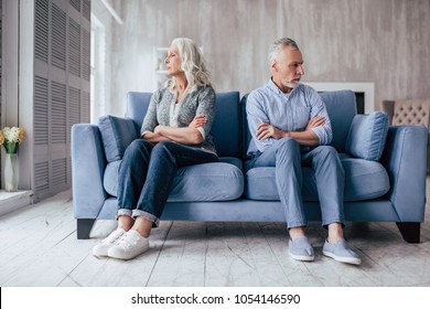 Senior couple at home. Handsome old man and attractive old woman are having relationship problems. Sitting on sofa together and looking to opposite sides. - Powered by Shutterstock