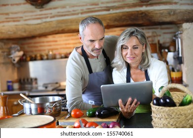Senior Couple In Home Kitchen Looking At Tablet