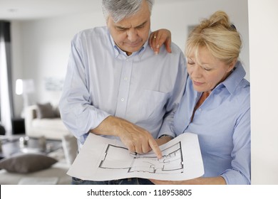 Senior Couple At Home Looking At Blueprint