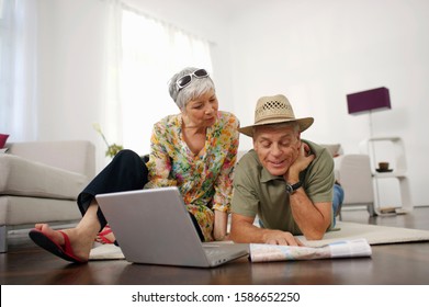 Senior Couple At Home Looking At Map And Laptop