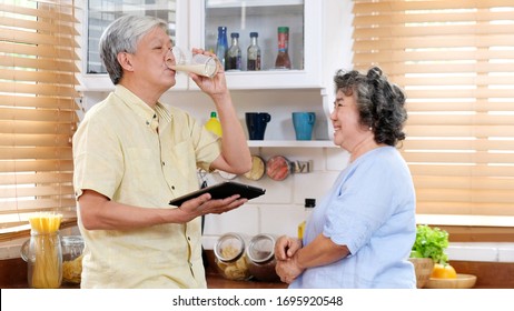 Senior Couple At Home, Old Asian Man Drinking Milk At Kitchen Standing With Old Woman, Elderly Asia Male Holding Glass Of Milk For Healthy Dairy With His Wife, Retirement People Family Lifestyle