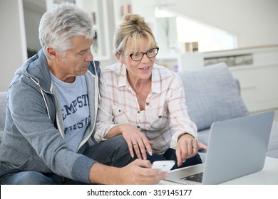 Senior couple at home websurfing on laptop computer
