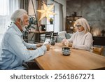 senior couple husband and wife play cards with husband on wooden table at home