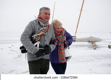 Senior Couple With Ice Skates Walking On Frozen Lake