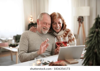 Senior Couple Indoors At Home At Christmas, Having Video Call With Family.