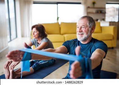 A Senior Couple Indoors At Home, Doing Exercise On The Floor.