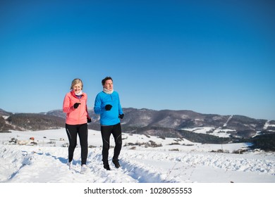 Senior Couple Jogging In Winter Nature.