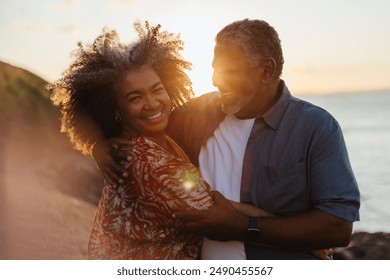 Senior couple joyfully embracing at sunset, capturing a moment of love and warmth by the sea shore. - Powered by Shutterstock