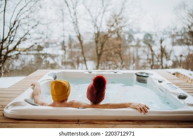 Senior couple in kintted cap enjoying together outdoor bathtub at their terrace during cold winter day. - Powered by Shutterstock