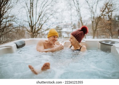 Senior couple in kintted cap enjoying together outdoor bathtub at their terrace during cold winter day. - Powered by Shutterstock