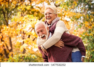 Senior couple laughing and having fun in autumn park. After all these years as at the first meeting