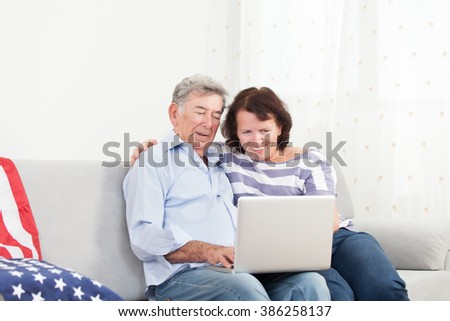Senior couple laughing while using laptop at home