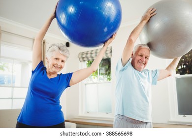 Senior Couple Lifting Exercise Ball While Exercising