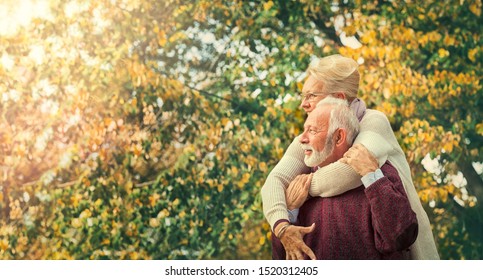 Senior couple looking happy against autumn background. Positive emotion, embracing and senior love concept.