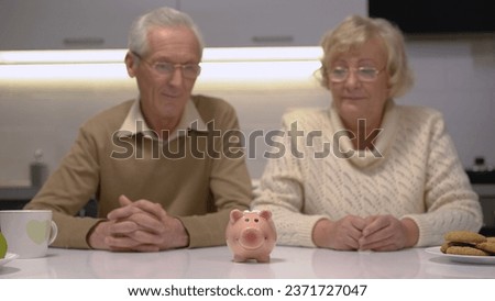 A senior couple looking at a piggy bank standing on the table while planning their family budget
