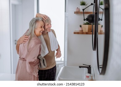 Senior Couple In Love In Bathroom, Looking At Mirror And Having Fun, Morning Routine Concept.