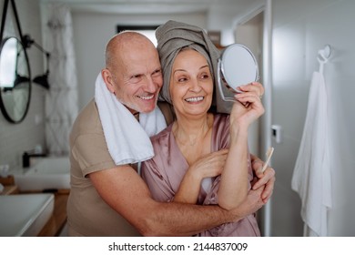 Senior Couple In Love In Bathroom, Looking At Mirror And Smiling, Morning Routine Concept.