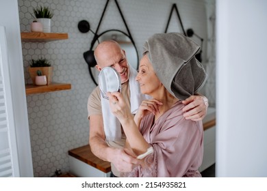 Senior Couple In Love In Bathroom, Looking At Mirror And Smiling, Morning Routine Concept.