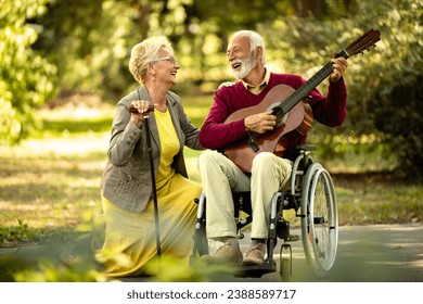 Senior couple love and happiness. Elderly man in wheelchair playing guitar to his lovely wife. - Powered by Shutterstock