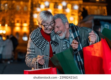 Senior couple in love having fun time while shopping at Christmas market.