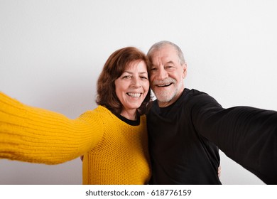 Senior Couple In Love Hugging, Taking Selfie. Studio Shot.