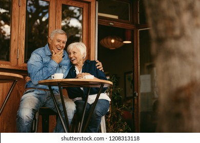 Senior Couple In Love Sitting In Cafe Talking And Having Fun. Happy Retirement Couple Relaxing At Coffee Shop.