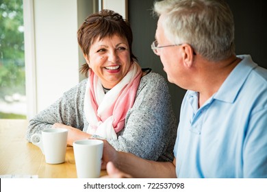 Senior couple in love sitting in cafe, drinking coffee, talking, laughing and having fun. Happy people in retirement concept.