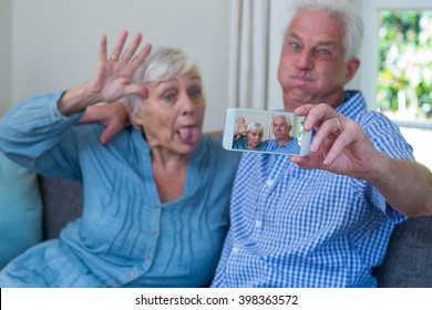 Senior couple making faces while taking selfie at home - Powered by Shutterstock