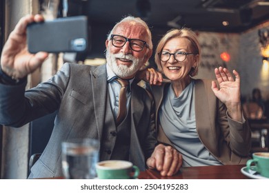 Senior couple mature man and woman caucasian husband and wife taking selfie photos self portraits or video call while sit in cafe or restaurant cafeteria - Powered by Shutterstock