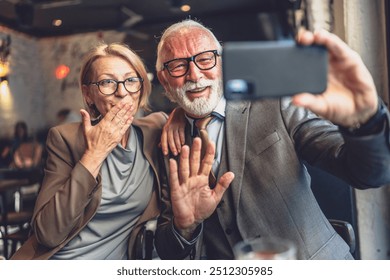 Senior couple mature man and woman caucasian husband and wife taking selfie photos self portraits or video call while sit in cafe or restaurant cafeteria - Powered by Shutterstock