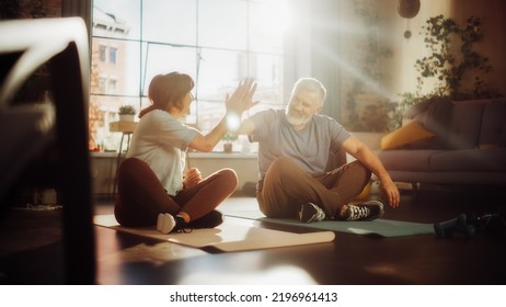 Senior Couple Meditating and Motivating Each Other with High Five After Morning Exercises at Home in Sunny Living Room. Healthy Lifestyle, Fitness, Recreation, Wellbeing and Retirement.