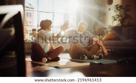 Senior Couple Meditating and Motivating Each Other with High Five After Morning Exercises at Home in Sunny Living Room. Healthy Lifestyle, Fitness, Recreation, Wellbeing and Retirement. Foto stock © 