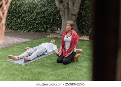 Senior couple meditating together on yoga mats in wonderfully peaceful scene showcasing the art of meditation and relaxation within a tranquil garden environment. Wide angle, horizontal - Powered by Shutterstock