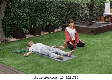 Senior couple meditating together on yoga mats in wonderfully peaceful scene showcasing the art of meditation and relaxation within a tranquil garden environment. Wide angle, horizontal - Powered by Shutterstock