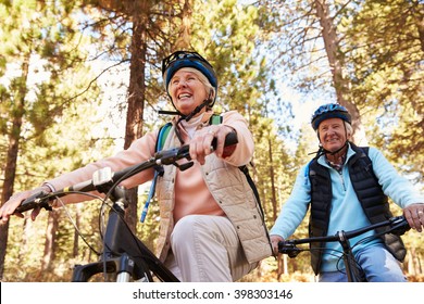 Senior Couple Mountain Biking On A Forest Trail, Low Angle