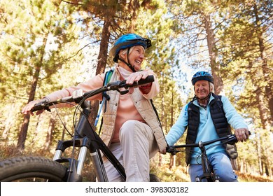 Senior Couple Mountain Biking On A Forest Trail, Low Angle