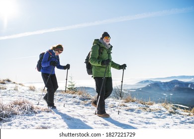 Senior couple with nordic walking poles hiking in snow-covered winter nature. - Shutterstock ID 1827221729