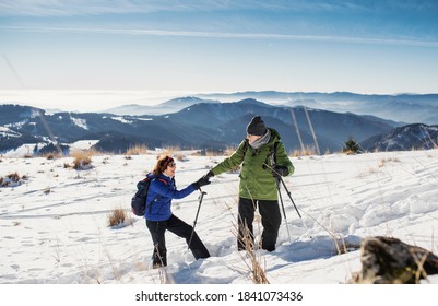 Senior Couple With Nordic Walking Poles Hiking In Snow-covered Winter Nature.