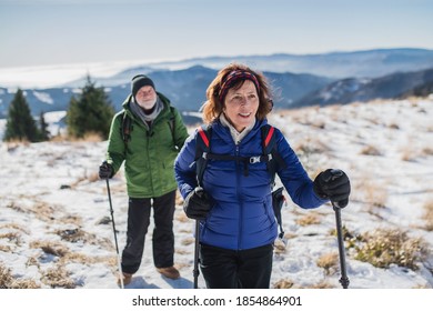 Senior Couple With Nordic Walking Poles Hiking In Snow-covered Winter Nature.