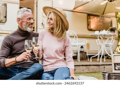 Senior couple on a date during picnic looking at each other with love drinking wine in the porch of their camper van. Spouses celebrating anniversary on a trip holiday by trailer motor home - Powered by Shutterstock