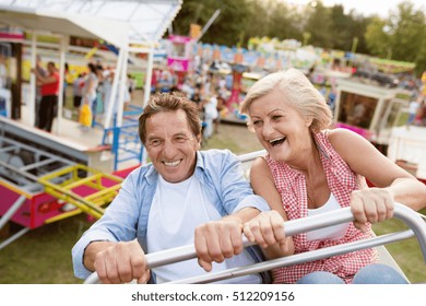 Senior Couple On A Ride In Amusement Park